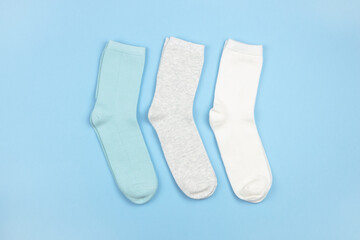 Colored children's socks without pattern, blue, gray, white on blue background with copy space, flatly, minimal style. Concept clothing, housekeeping, sorting, decluttering, organizing