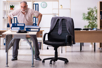 Old male employee doing physical exercises at workplace