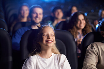 Young teenage girl laughing in movie theater.