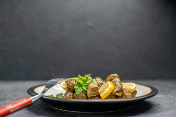 front view azerbaijani cuisine dolma with lemon slices and parsley leaves on white oval plate and...