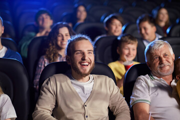Young laughing man in movie theater.