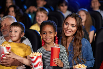 Mother with african kid on knees in cinema.