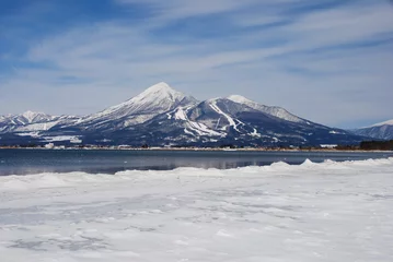 Fotobehang 冬晴れの会津磐梯山と猪苗代湖の湖岸の雪原 © palzafenon