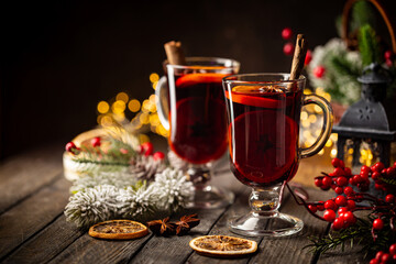 christmas hot mulled wine with spices and fruits on wooden background with christmas lights