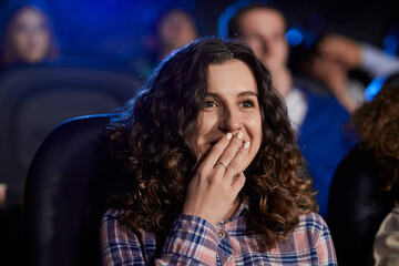 Young laughing girl watching comedy in movie theater.