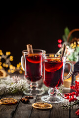 christmas hot mulled wine with spices and fruits on wooden background with christmas lights