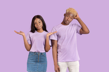 Who knows. Portrait of young black couple shrugging shoulders on violet studio background