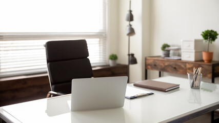 Close up view of empty employee desk workplace with computer and documents on it. Crop image of office worker table workspace with laptop and papers and journal. Business, employment concept.