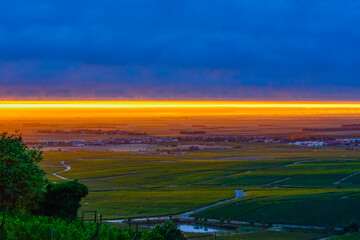 Amazing sunrise on rainy day over green grand cru vineyards near Epernay, region Champagne, France. Cultivation of white chardonnay wine grape on chalky soils of Cote des Blancs.
