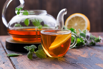 Transparent cup of tea with honey and mint on wooden background