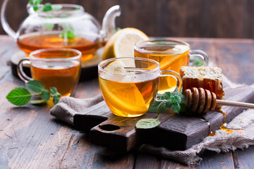 Transparent cup of tea with honey and mint on wooden background