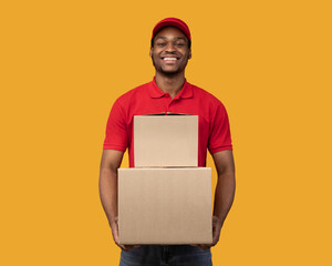 Black delivery man holding pile of boxes