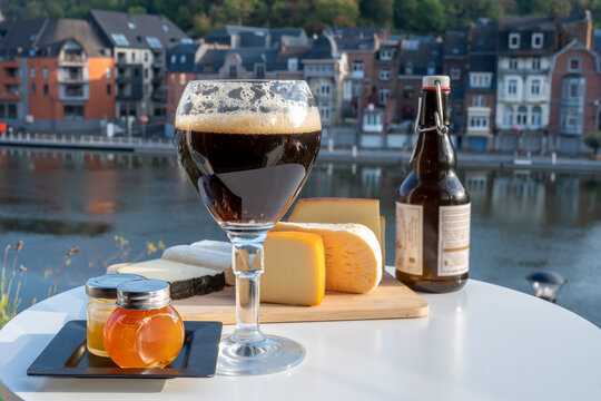 Drinking of dark and strong Belgian abbey beer with cheeses with nice view on Maas river and town Dinant, Belgium