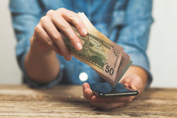 Hands hold a smartphone and money. Online loan of money in debt. Credit in the Internet bank...