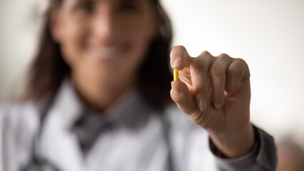 Close up blurred view of doctor hold pill or tablet recommend medicines for good health. GP or physician show drug medication, advise dietary supplements or dose of vitamins. Healthy life concept.