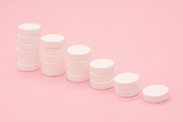 A stack of pills on a pink background. Growth graph made of stacked white pills