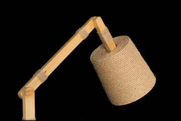 Handmade lamp made of pine wood sticks and hemp string wrapped around a plastic yogurt container