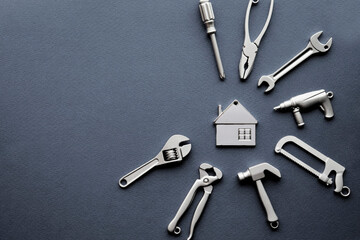 Metal tools surrounded the house. Concept of home renovation. Construction, repair work. Restoration. Repair services. Hammer, wrench, screwdriver.