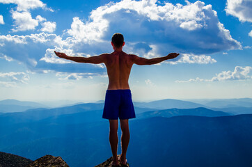 man stands on top of a mountain with open hand - 400801214