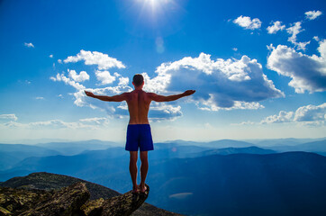 man stands on top of a mountain with open hand - 400801842