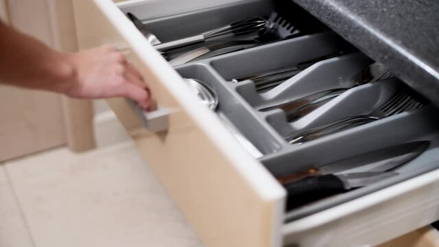 Clean table forks, spoons and knives in a drawer in the kitchen