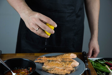 Chief cook squeezes lemon on carved fish baked in salt crust. Seafood cooking. Salmon or seabass...