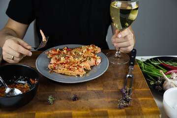 Man eats carved fish baked in salt crust under chili sauce. Seafood cooking. Salmon or seabass under salt crust with vegetables with wine.