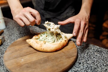 the hands of the cook prepare khachapuri on the kitchen table. cook a traditional Georgian treat of...