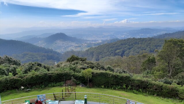 beautiful scenic view from dottabetta peak of green forest hill mountain with blue sky rain mist clouds background