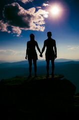 a loving couple holding hands at the top of a mountain. - 400803228