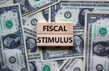 Fiscal stimulus symbol. Concept words 'fiscal stimulus' on wooden blocks on a beautiful background from dollar bills. Business and fiscal stimulus concept.