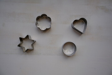 Silver metal star-shaped, heart-shaped, round, and flower-shaped biscuit cutters for baking on...