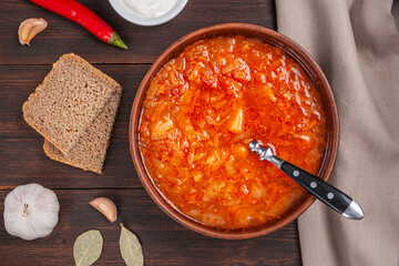 Tasty beetroot soup in bowl on wooden background.