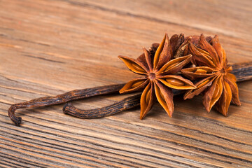 Star anise with vanilla beans on a wooden background.