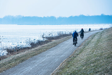 People cycling along the frozen lake in the Netherlands