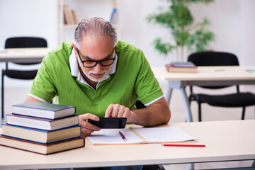 Old male student preparing for exams in the classroom