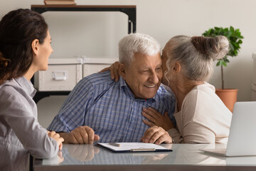 Excited elderly couple celebrate health insurance deal closing with consultant at meeting. Happy...