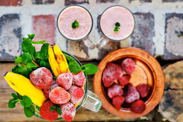 Strawberries, bananas, mint leaves in a mixer bowl are ingredients for making a milkshake. Flat lay, selective focus on ingredients. Healthy food or snack top view