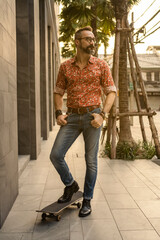 Male model with a hipster look standing on a skateboard.