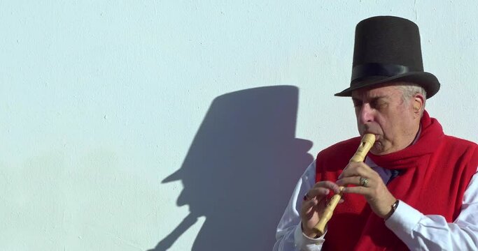 Actor in cylinder hat and sunglasses entertains people by playing soprano recorder at Christmas in Los Angeles, California, 4K