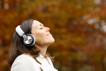 Adult woman breathing fresh air with headphones in autumn