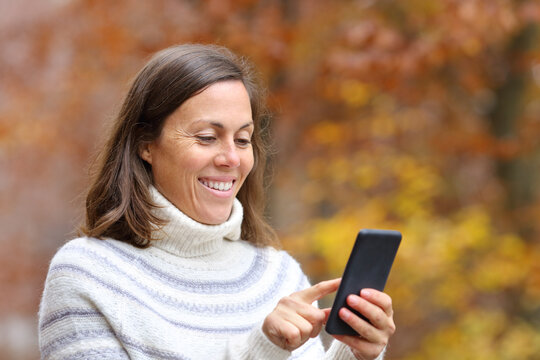 Happy Adult Woman Using Smart Phone In Autumn In A Park