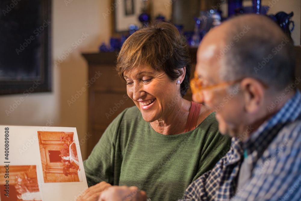 Wall mural Loving senior couple look at their old wedding photo album.