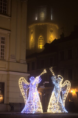 Christmas illuminations in the shape of angels against the background of the Trinitarian Tower in Lublin