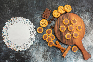 overhead shot of cookies on wooden platter with a piece of white lace on grey background