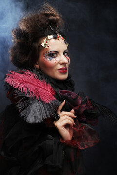 Young woman with creative makeup and and hairdo posing on dark background. Party time and halloween.