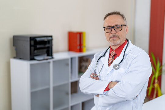 Male medic looking at camera while sitting cross hands at table in modern office. Up to date clinic.