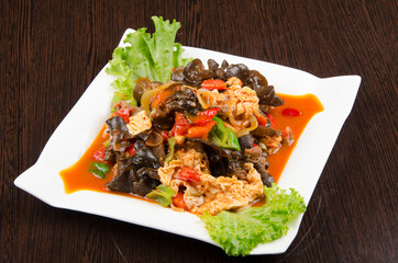 fried chicken with garnish and salad in sauce, with vegetables, asian traditional cuisine, in a white plate on a wooden background