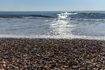 Sparkling waves on the beach hits the pebble beach in Antalya Turkey, Holiday and Travel concept, sunny and blue sky, nobody, no people, space for text, selective focus.
