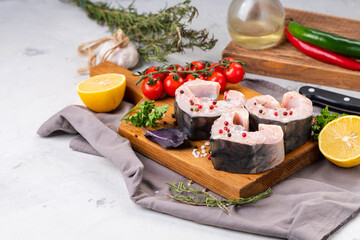 Fresh organic seafood. Raw sturgeon steaks on a cutting Board with spices and vegetables. On a gray...
